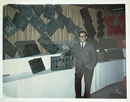 Photo of a man in a suit with a display of boxes and bags.