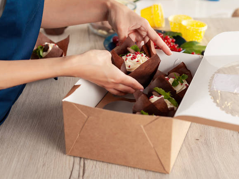 Baked good in a box being handed to someone else.